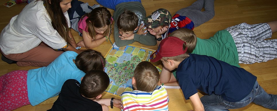 Credit: Jungschar Österreich Kinder liegen im Kreis auf dem Boden und schauen auf eine Karte.
