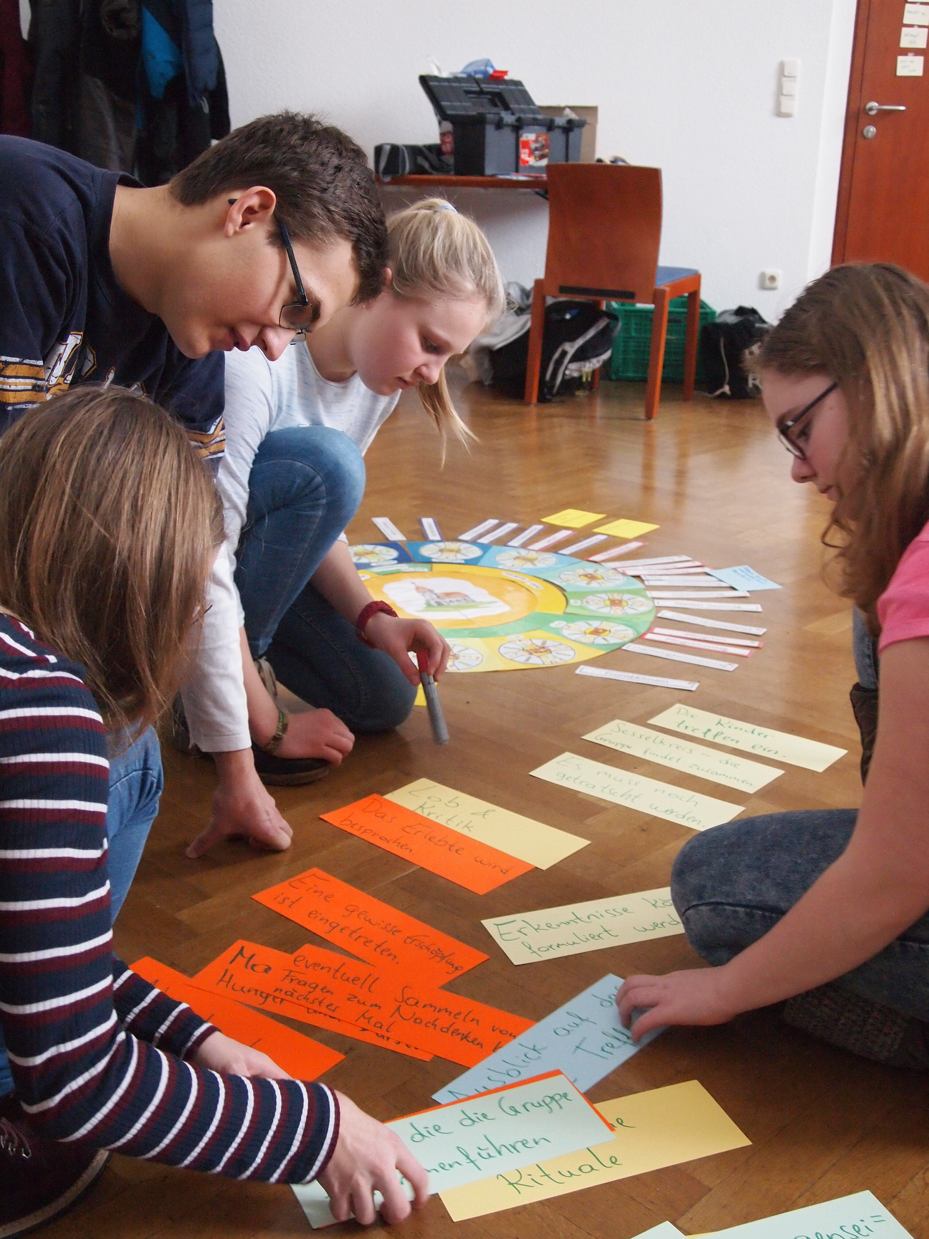 Kinder arbeiten mit dem Jahreskreis, der am Boden aufgelegt ist