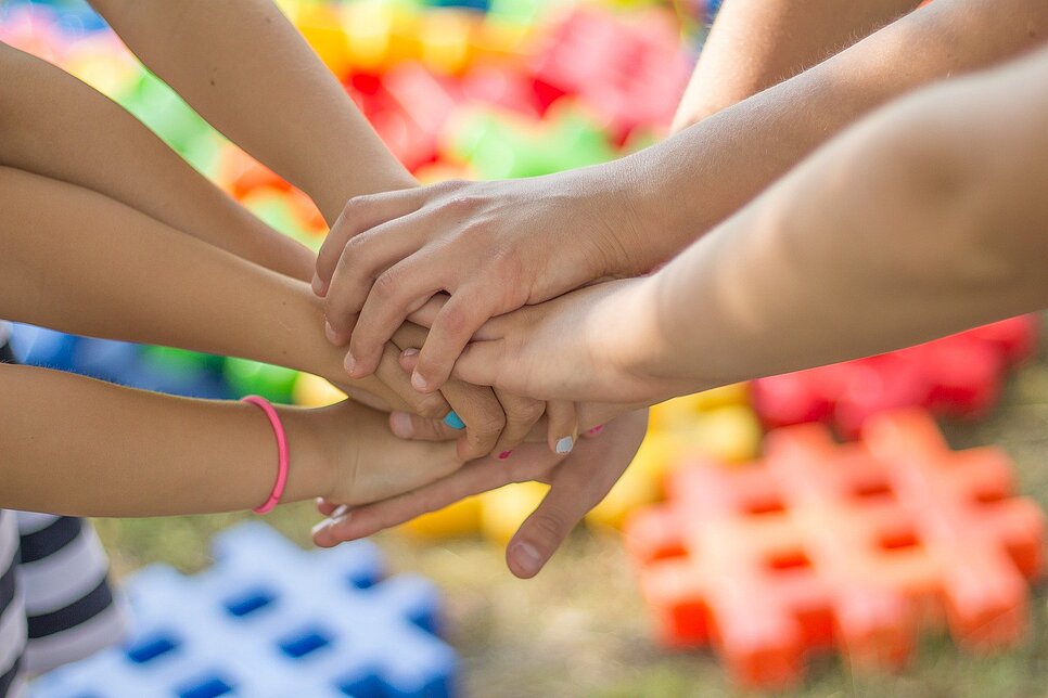 Vier Kinder haben ihre Hände aufeinander gelegt.