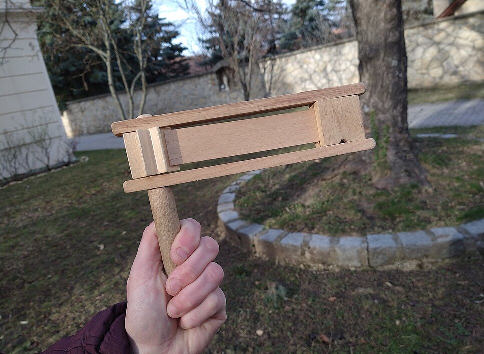 Jemand hält eine kleine Ratsche in der Hand.